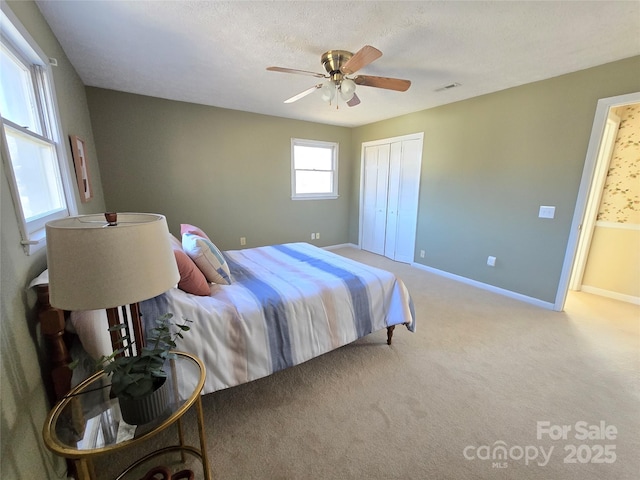 bedroom with ceiling fan, connected bathroom, a closet, light colored carpet, and a textured ceiling