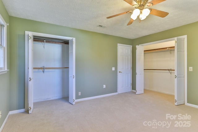 unfurnished bedroom featuring light carpet, ceiling fan, and a textured ceiling