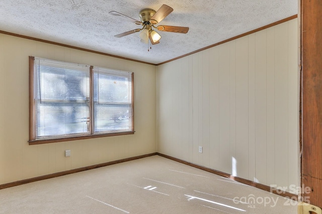 unfurnished room with a textured ceiling, ceiling fan, crown molding, and light colored carpet