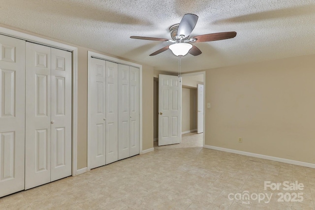 unfurnished bedroom featuring a textured ceiling, ceiling fan, and two closets