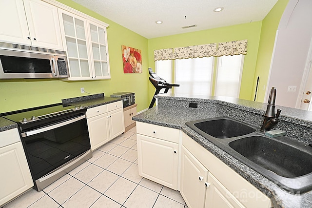 kitchen featuring white cabinets, light tile patterned floors, electric range oven, and sink