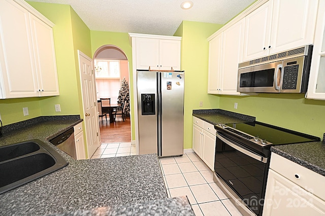 kitchen featuring appliances with stainless steel finishes, light tile patterned floors, and white cabinetry