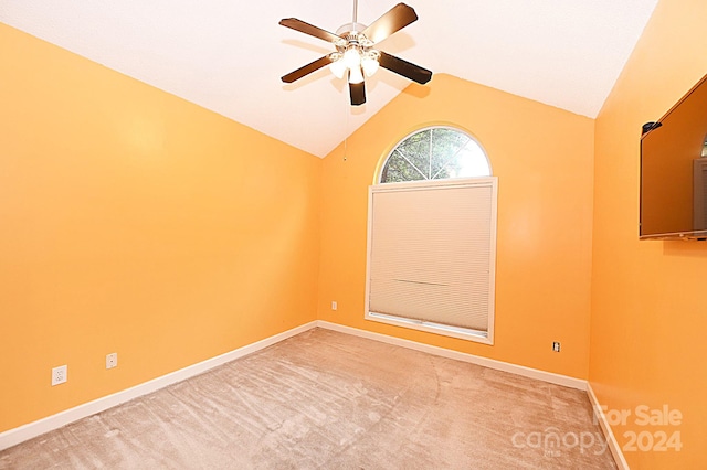 carpeted spare room with ceiling fan and vaulted ceiling