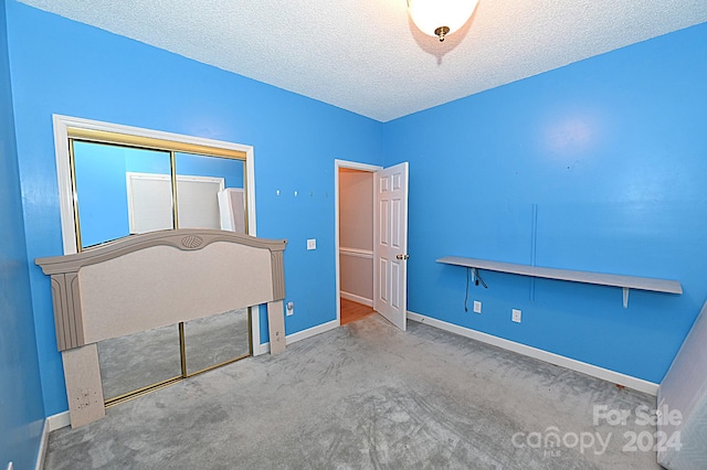 unfurnished bedroom with carpet flooring, a closet, and a textured ceiling