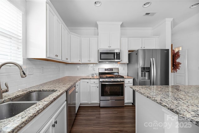 kitchen with white cabinets, stainless steel appliances, light stone counters, sink, and tasteful backsplash