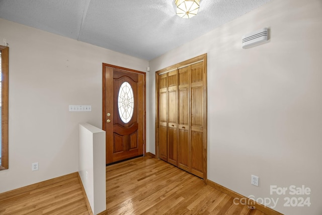 foyer entrance featuring light hardwood / wood-style floors and a textured ceiling