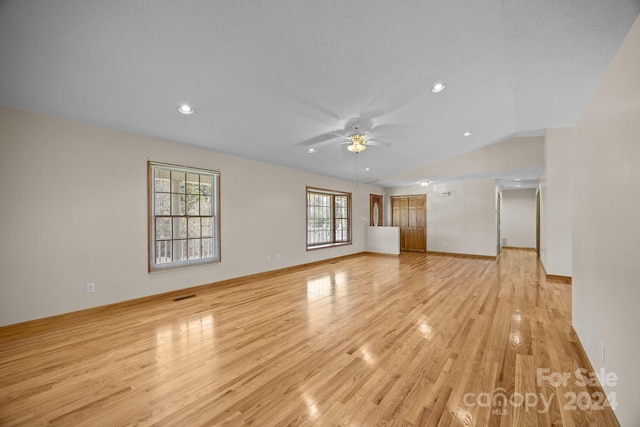 unfurnished living room featuring a textured ceiling, light wood-type flooring, vaulted ceiling, and ceiling fan