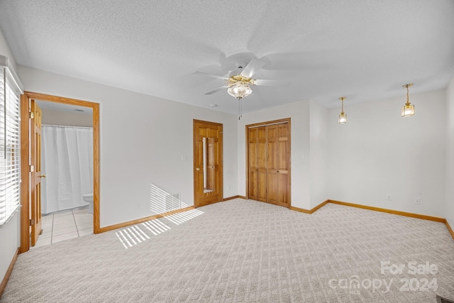 spare room featuring ceiling fan, light carpet, and a textured ceiling