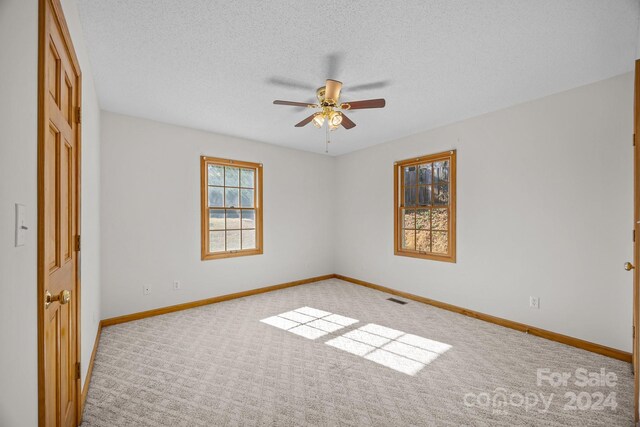 unfurnished bedroom featuring ceiling fan, light carpet, and a textured ceiling