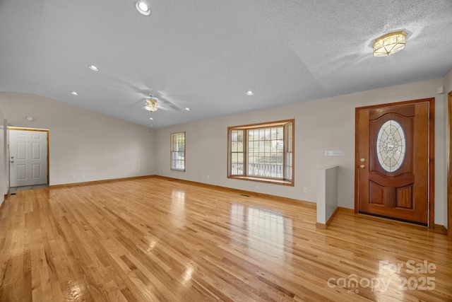 foyer featuring light wood-style floors, a ceiling fan, baseboards, and lofted ceiling