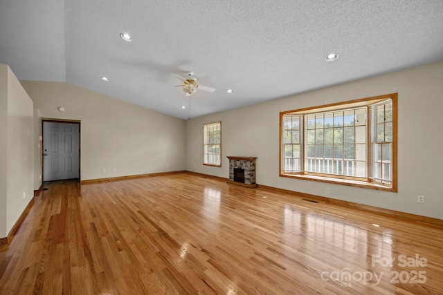 unfurnished living room featuring visible vents, a stone fireplace, ceiling fan, light wood finished floors, and vaulted ceiling