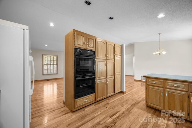 kitchen featuring an inviting chandelier, dobule oven black, decorative light fixtures, freestanding refrigerator, and light wood-style floors