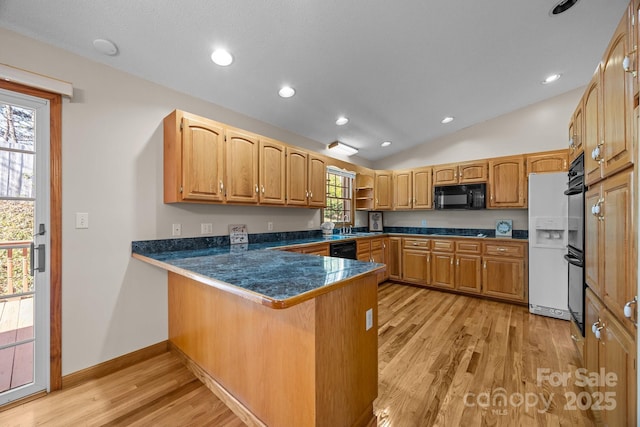 kitchen with dark countertops, light wood finished floors, a peninsula, vaulted ceiling, and black appliances