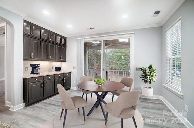 dining area with light hardwood / wood-style floors, a wealth of natural light, and ornamental molding