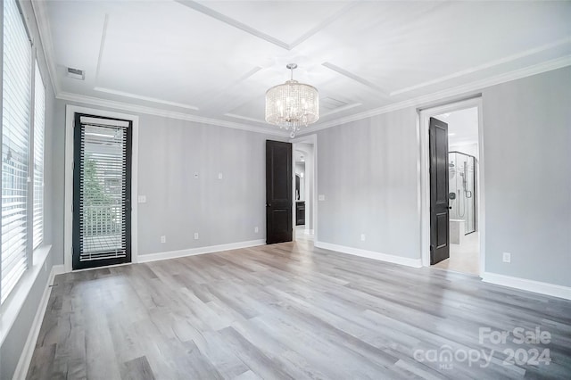 spare room with light hardwood / wood-style floors, crown molding, and an inviting chandelier