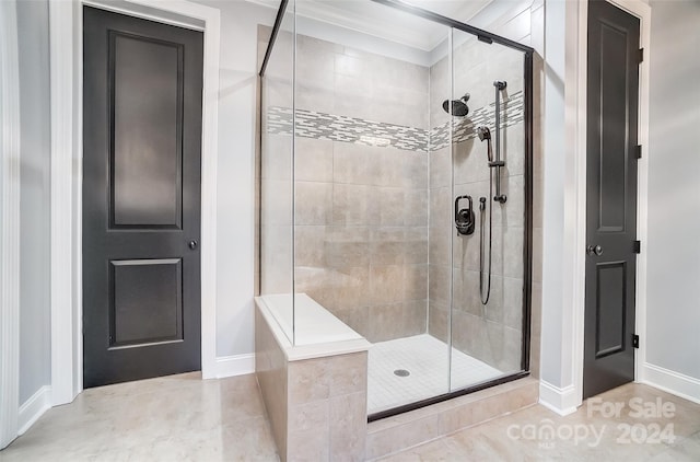 bathroom featuring tile patterned flooring, ornamental molding, and a shower with shower door