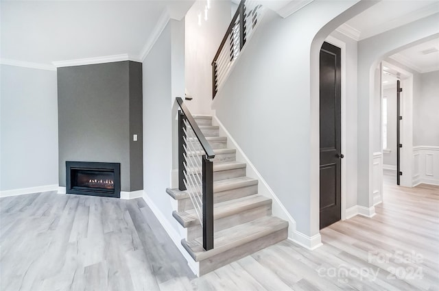 stairway with hardwood / wood-style flooring and crown molding