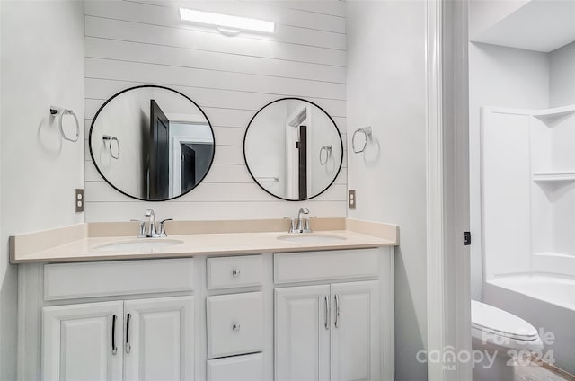 bathroom with vanity, toilet, and wooden walls