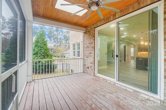 unfurnished sunroom featuring ceiling fan, a skylight, a wealth of natural light, and wood ceiling