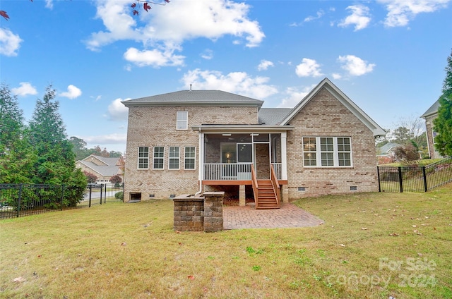 rear view of house featuring a sunroom, a patio area, and a lawn