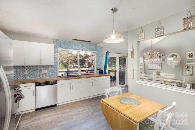 kitchen featuring light wood finished floors, butcher block countertops, a sink, appliances with stainless steel finishes, and white cabinetry