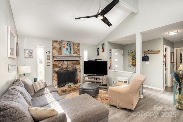 living room with wood finished floors, baseboards, a ceiling fan, lofted ceiling with beams, and a fireplace