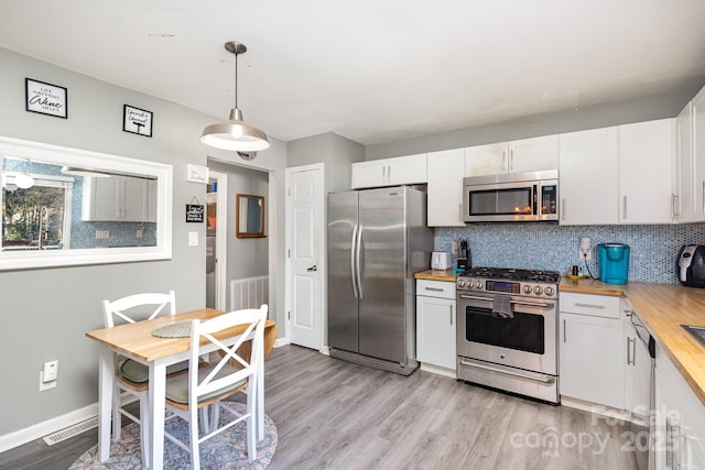 kitchen featuring visible vents, butcher block counters, stainless steel appliances, and decorative backsplash