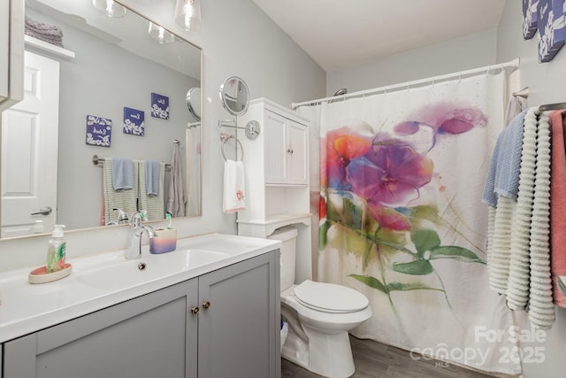 bathroom featuring curtained shower, toilet, wood finished floors, and vanity