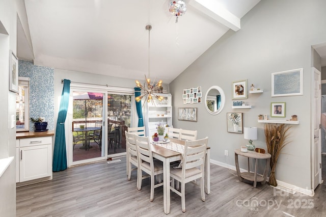 dining room with lofted ceiling with beams, light wood-type flooring, baseboards, and a chandelier