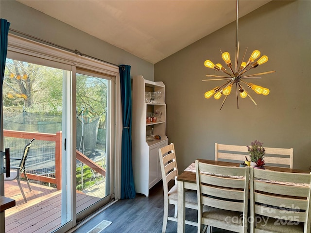 unfurnished dining area with visible vents, wood finished floors, lofted ceiling, and a chandelier