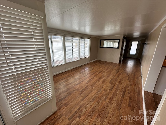 unfurnished living room featuring dark hardwood / wood-style flooring, a textured ceiling, and a wealth of natural light