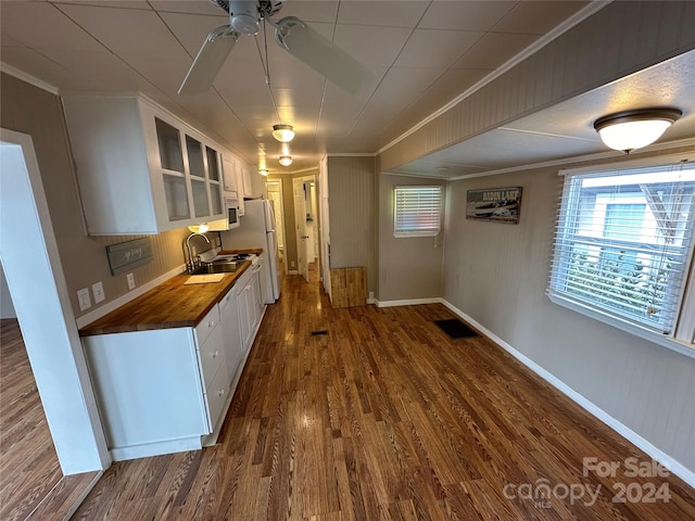 kitchen featuring ornamental molding, white appliances, dark wood-type flooring, butcher block countertops, and white cabinetry