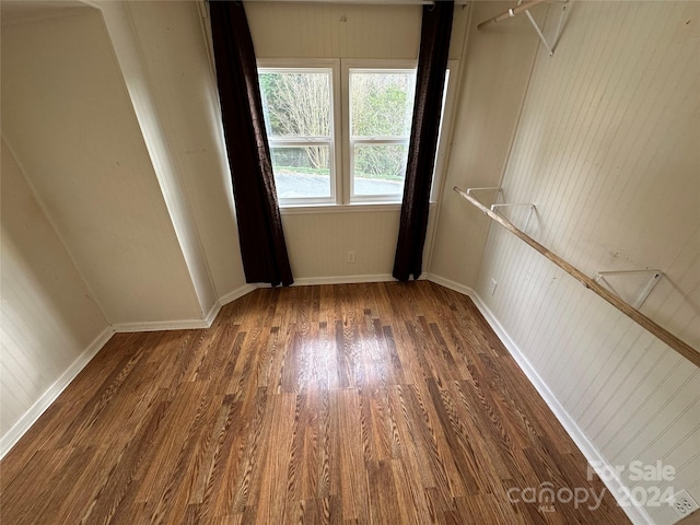 unfurnished room with dark hardwood / wood-style floors and wood walls