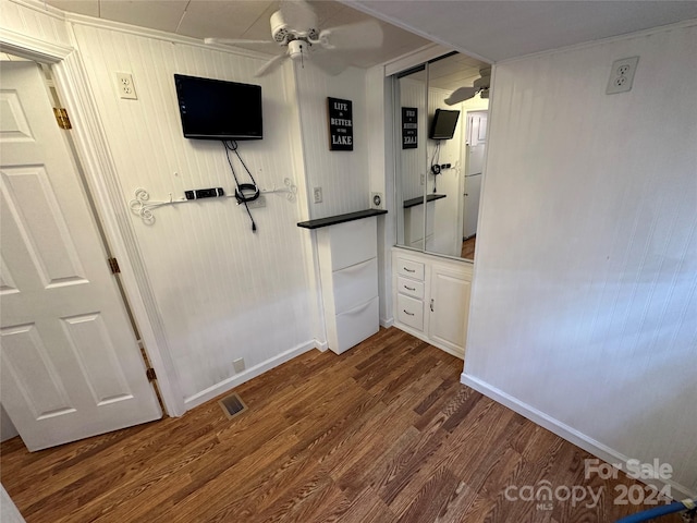 unfurnished bedroom featuring hardwood / wood-style flooring, a closet, wooden walls, and ceiling fan