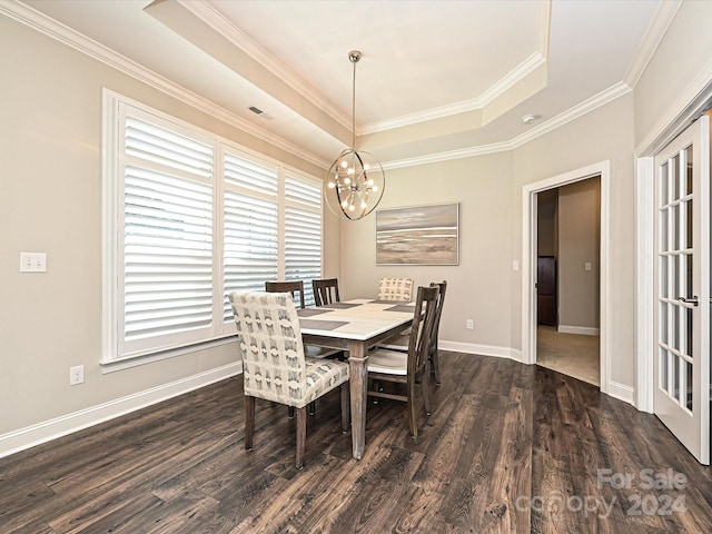 dining space featuring dark hardwood / wood-style flooring, an inviting chandelier, a raised ceiling, and ornamental molding