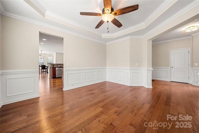 unfurnished room with ornamental molding, wainscoting, wood finished floors, and a ceiling fan