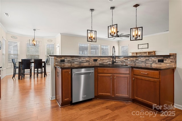 kitchen with backsplash, a sink, visible vents, and brown cabinets