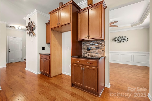 kitchen with light wood-style floors, ornamental molding, and brown cabinets