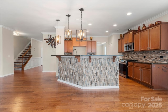 kitchen featuring brown cabinets, stainless steel appliances, backsplash, light wood-style flooring, and ornamental molding