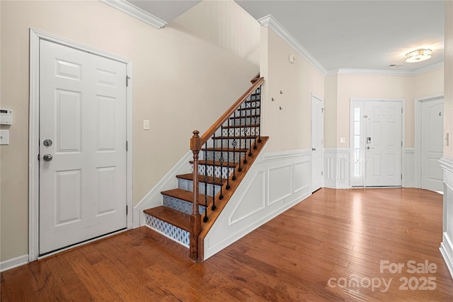 entrance foyer featuring crown molding, stairway, and wood finished floors