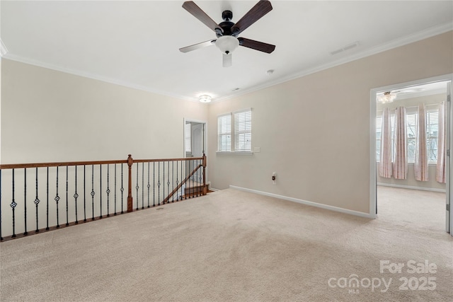 carpeted spare room featuring ornamental molding, a ceiling fan, visible vents, and baseboards