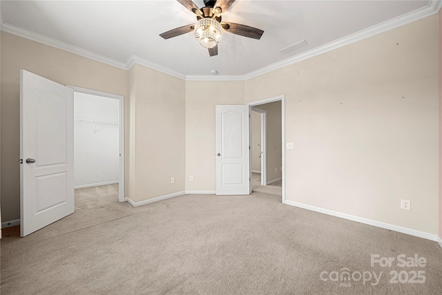 unfurnished bedroom with light colored carpet, a spacious closet, ornamental molding, a ceiling fan, and baseboards