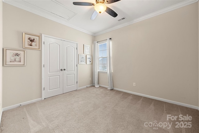 unfurnished bedroom with carpet floors, visible vents, baseboards, ornamental molding, and attic access