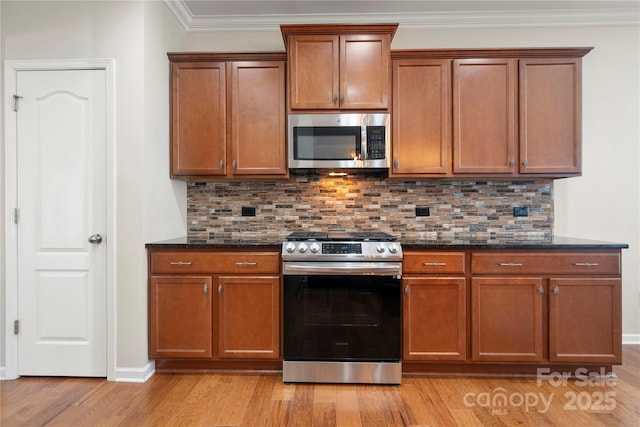 kitchen featuring light wood-type flooring, appliances with stainless steel finishes, decorative backsplash, and crown molding