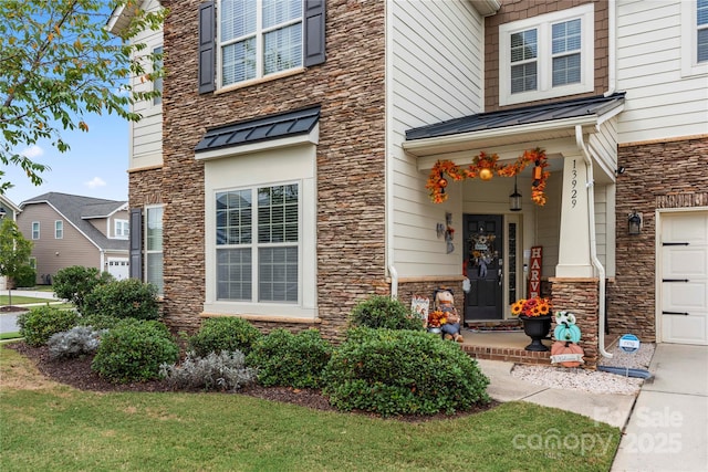 doorway to property featuring a garage, a standing seam roof, metal roof, and stone siding