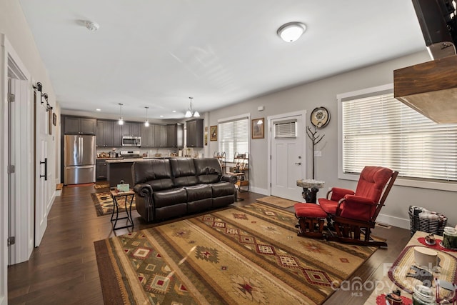 living room with dark hardwood / wood-style flooring, a barn door, and an AC wall unit