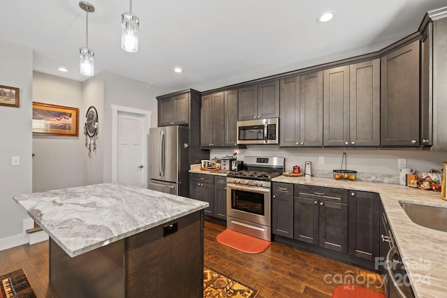 kitchen featuring hanging light fixtures, dark hardwood / wood-style flooring, a center island, dark brown cabinets, and stainless steel appliances