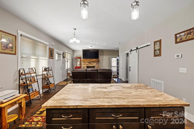 kitchen with dark hardwood / wood-style flooring, a barn door, hanging light fixtures, and a healthy amount of sunlight