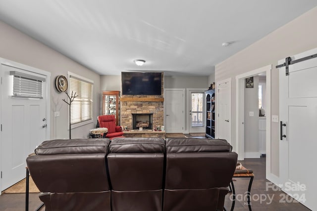 living room with an AC wall unit, a barn door, a stone fireplace, and dark hardwood / wood-style floors