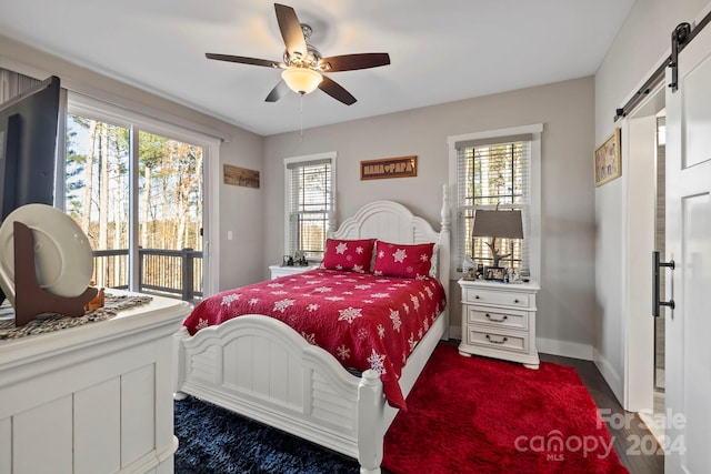 bedroom featuring a barn door, multiple windows, and ceiling fan